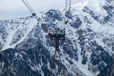 Overhead cable car over snowcapped mountains against sky