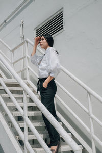 Full length of young woman standing on staircase