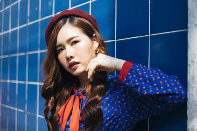 Portrait of young woman standing against wall