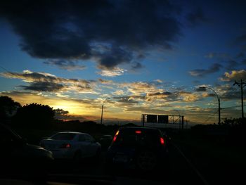 Cars on road against sky during sunset