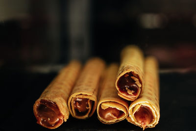 Sweet wafer rolls with chocolate condensed milk on dark background