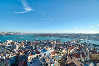 High angle view of townscape by sea against blue sky