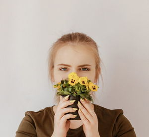 Portrait of woman holding plant against white background