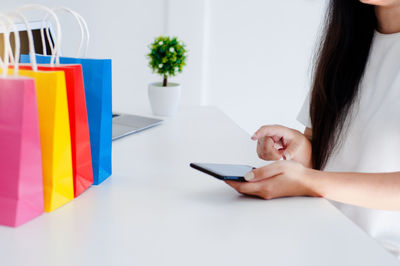 Midsection of woman holding smart phone on table