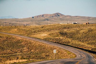 Road by field against clear sky