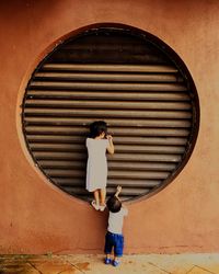 Rear view of children climbing on wall