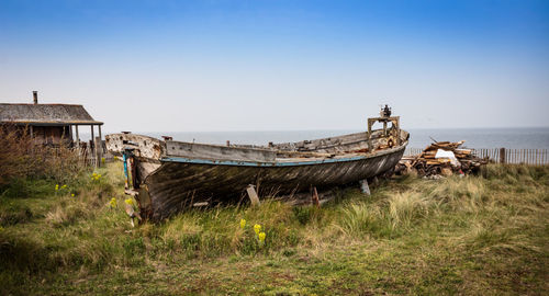 Abandoned ship on field against clear sky