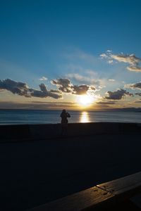 Silhouette man standing on beach against sky during sunset