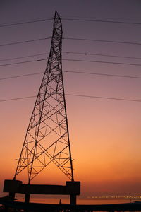 Low angle view of silhouette electricity pylon against sky during sunset