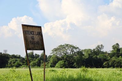 Information sign on field against sky