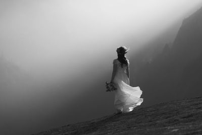 Full length of woman standing on mountain against sky
