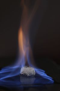 Close-up of burning candle against black background