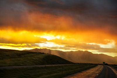 Empty road along countryside landscape at sunset