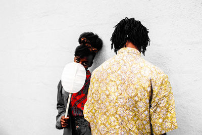 Rear view of friends standing against wall during winter