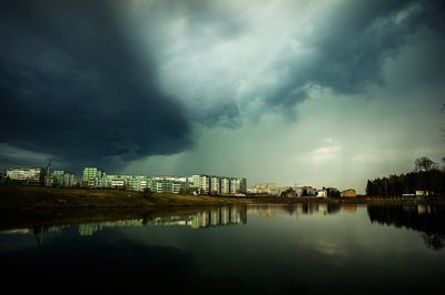 City at waterfront against cloudy sky