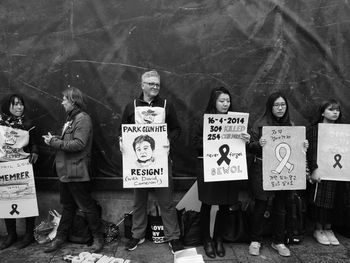 Woman holding poster while standing against wall