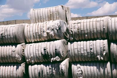 Stack of cotton on field against cloudy sky