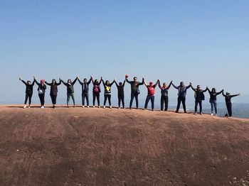 Group of people on beach against clear blue sky