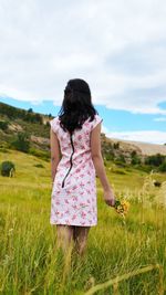 Rear view of woman standing on field against sky