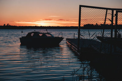 Silhouette boat moored on sea against sky during sunset