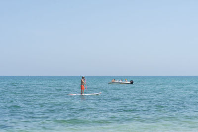 People in sea against clear sky