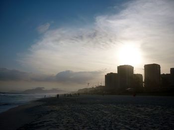 View of calm sea with silhouette buildings in background