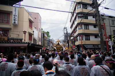 People walking on street amidst buildings in city