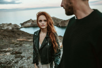 Portrait of beautiful woman standing at sea shore