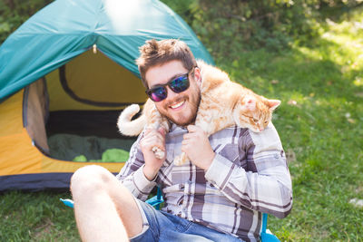 Man with cat wearing sunglasses while sitting outdoors