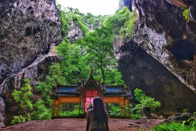 Rear view of woman standing on rock against trees