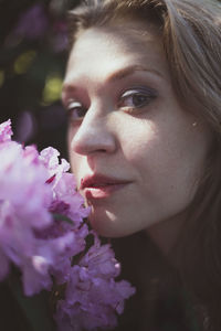 Close up lady pressing cheek against shrub with pink flowers portrait picture