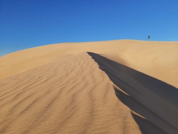 Sand dunes in desert against clear blue sky