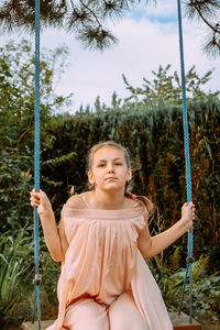 Low angle view of girl sitting on swing in playground