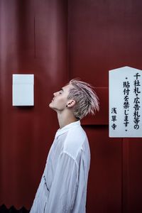 Side view of man standing against wall