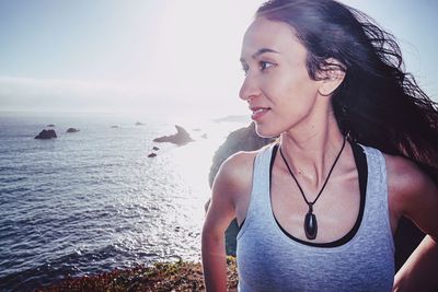 Portrait of young woman looking at sea against sky