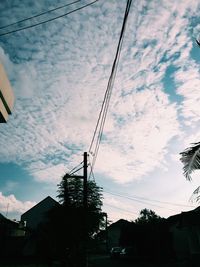 Low angle view of electricity pylon against cloudy sky
