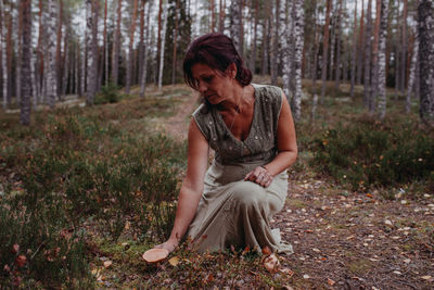 Young woman sitting on field in forest