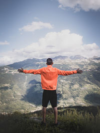 Rear view of man standing on mountain against sky