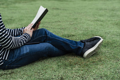 Low section of person relaxing on field