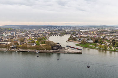 Aerial view of cityscape by river against sky