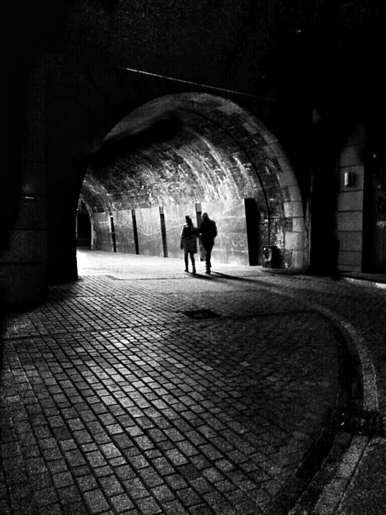 arch, indoors, rear view, men, walking, full length, architecture, person, the way forward, built structure, lifestyles, archway, cobblestone, leisure activity, silhouette, standing, tunnel, place of worship