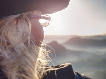 Young blond hair girl hiker sitting on a cliff and enjoy the sunset. saxon switzerland, germany.