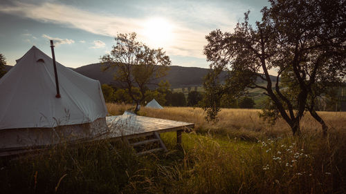 Tent on field against sky during sunset