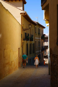 Rear view of people walking amidst buildings on alley