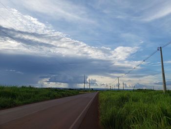 Road amidst field against sky