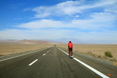 Rear view of man cycling on road