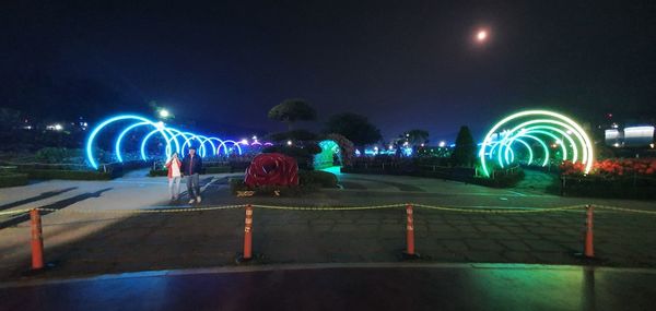 Rear view of people on illuminated street at night