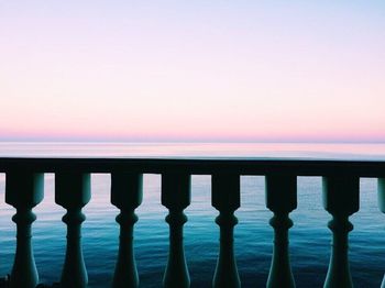 Swimming pool by sea against clear sky at sunset