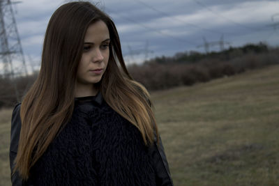 Close-up of beautiful young woman standing against sky