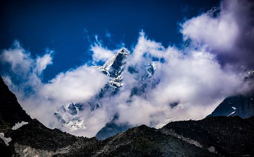 Low angle view of snowcapped mountains against blue sky